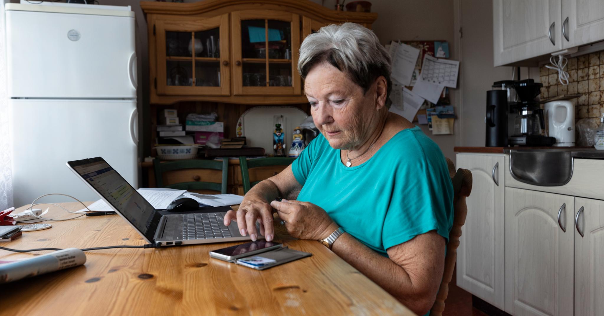 Gerd Møller (81) betaler regninger på PC-en ved kjøkkenbordet. Det er det ikke alle på hennes alder som klarer.