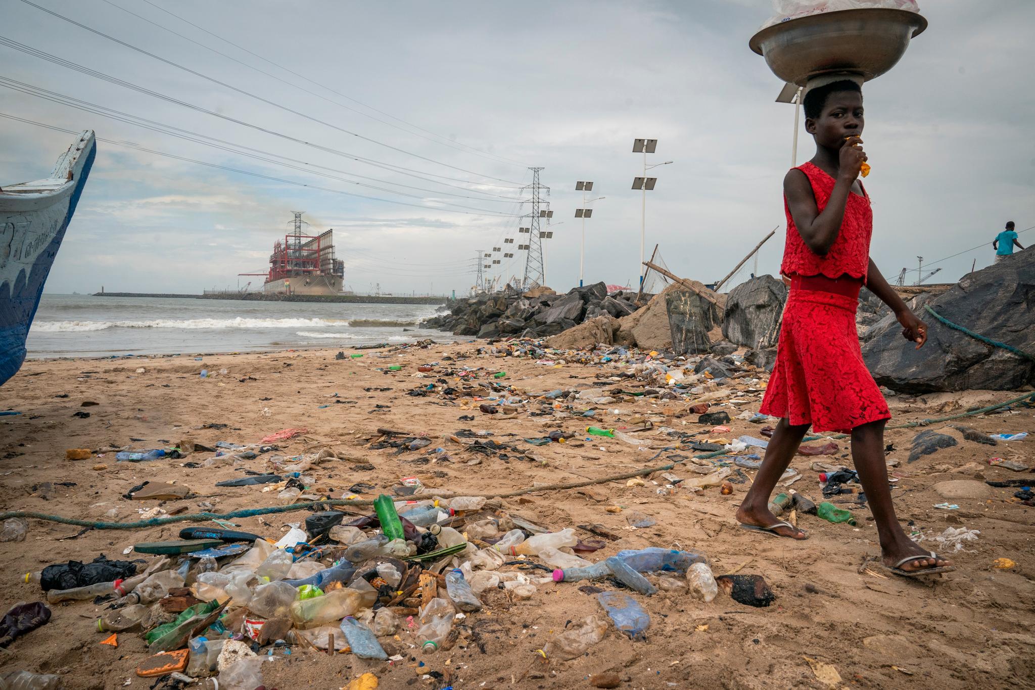 En jente går på en forsøplet strand i havnebyen Tema utenfor Accra i Ghana. Dårlig fiskeforvaltning og enorm forsøpling i havet og på land, hovedsakelig av plast, gjør at fiskerne tvinges til å ta lengre pauser fra fiskingen.