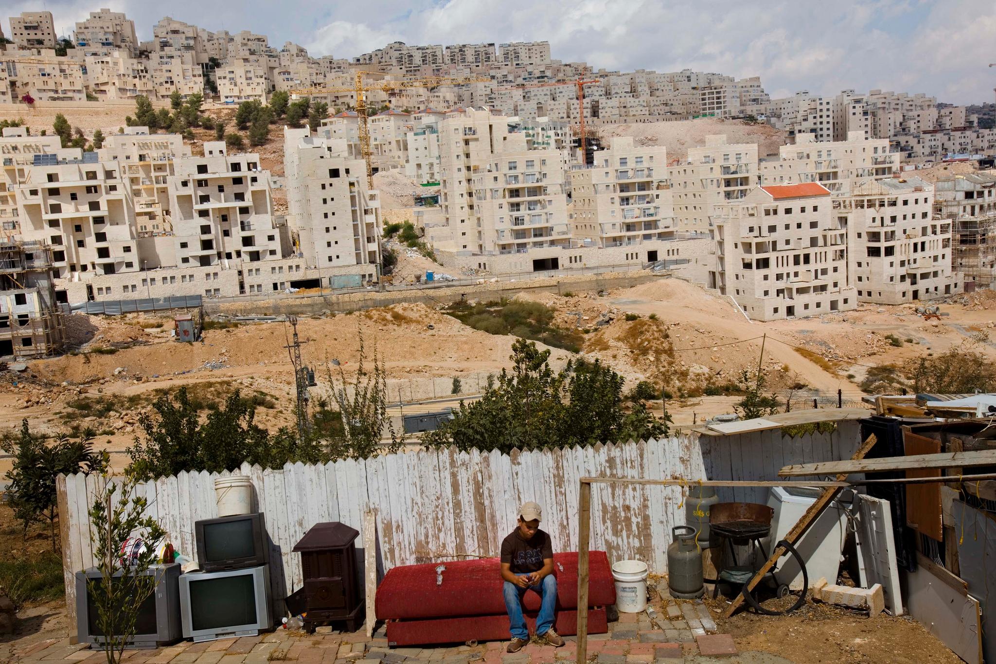 En palestinsk gutt sitter foran Har Homa-bosetningen. Bildet er tatt i 2009. 