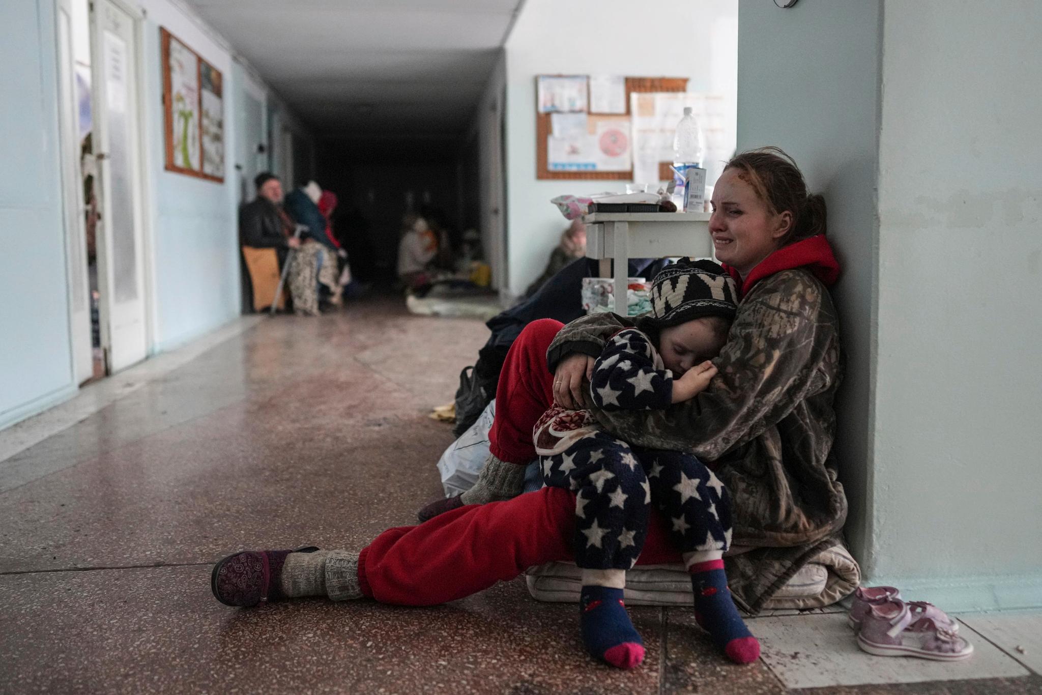 Anastasia Erashova gråter, med ett av sine barn på fanget, i korridoren i et sykehus i Mariupol. Hun mistet ett annet barn i et bombeangrep. Bildet er tatt fredag.