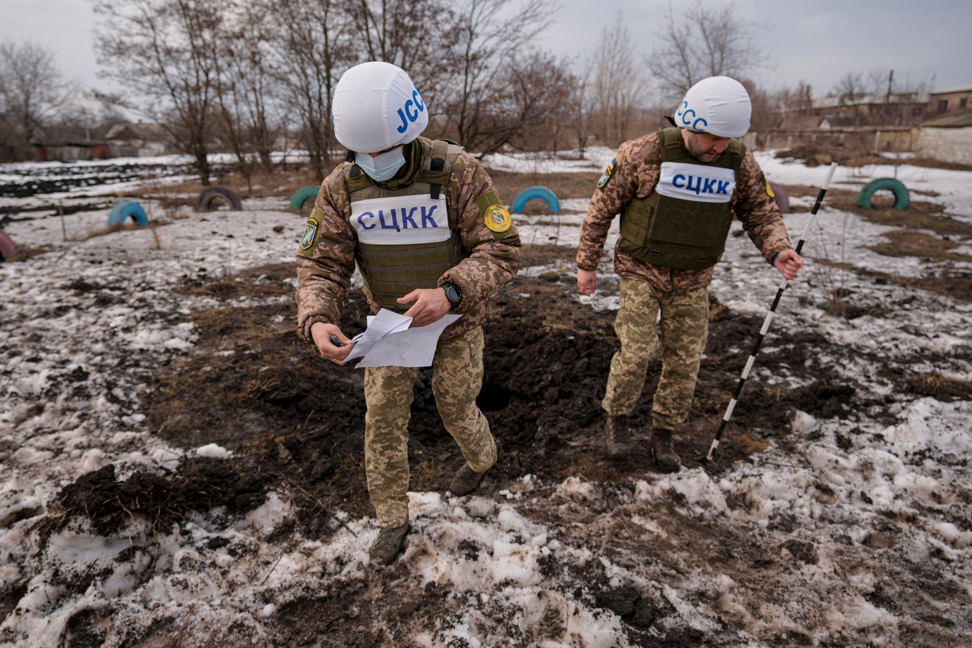 Medlemmer av Joint Centre for Control and Coordi nation undersøker et krater etter artilleriangrep i Luhanskregionen øst i Ukraina torsdag.