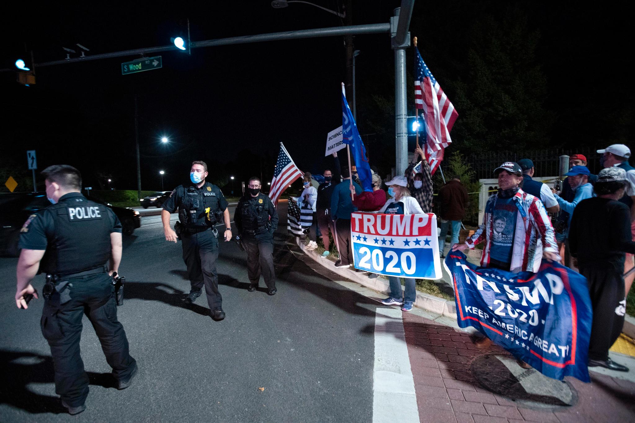 Tilhengere av president Donald Trump og politifolk utenfor hovedinngangen til det militære sykehuset Walter Reed fredag kveld lokal tid. 