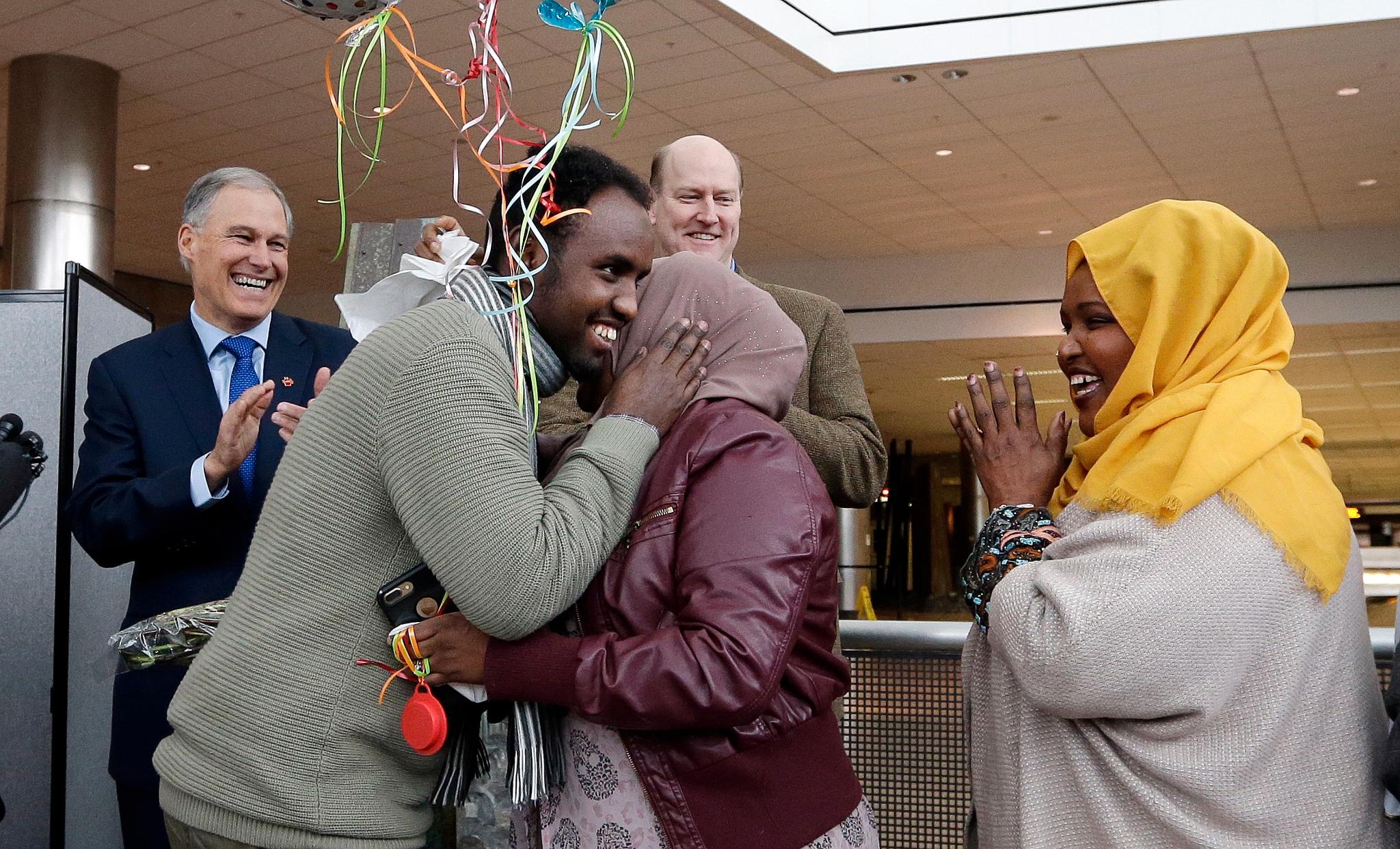 Isahaq Ahmed Rabi, (nr,. 2 f.v.) tas imot familiemedlemmer på Seattle Tacoma International Airport mandag. Rabi ble nektet innreise i forrige uke etter at innreiseforbundet ble iverksatt. Rabi er fra Somalia, men hans kone er amerikansk statsborger.  Bak applauderer representanter for delstatsmyndighetene i Washington, som fikk midlertidig stoppet innreiseforbudet.