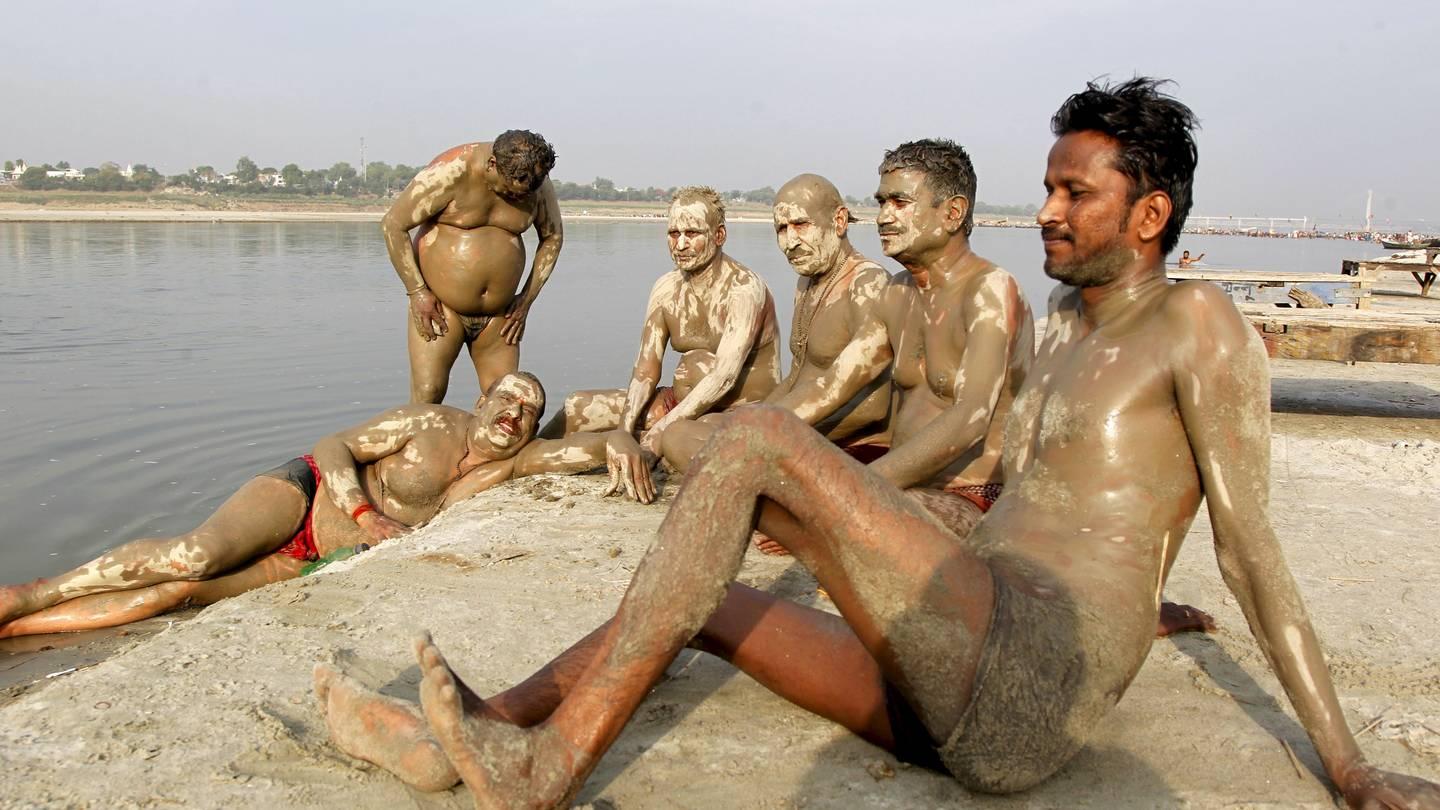Under hetebølgen i juni India smurte disse relativt avkledde mennene seg inn med gjørme fra Ganges for å kjøle seg ned.