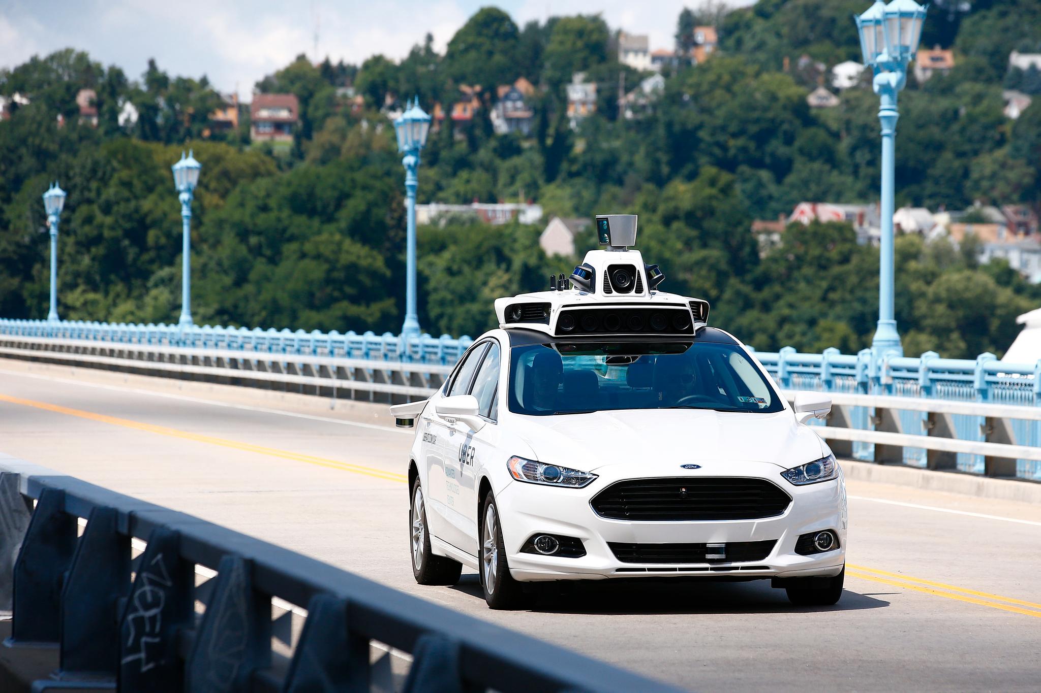 Uber-ansatte ute på prøvetur med en selvkjørende Ford Fusion hybridbil på en vei i Pittsburgh denne uken.