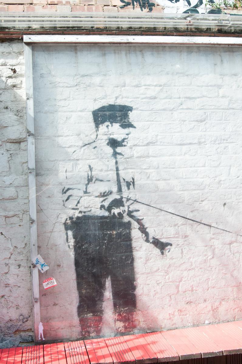 SJABLONGENS MESTER: Banksy klargjør sjablonger før han går ut å gjør selve jobben på gaten. Dette Banksy-arbeidet er nå bak pleksiplast og var laget med tillatelse fra eieren av (bar) veggen.