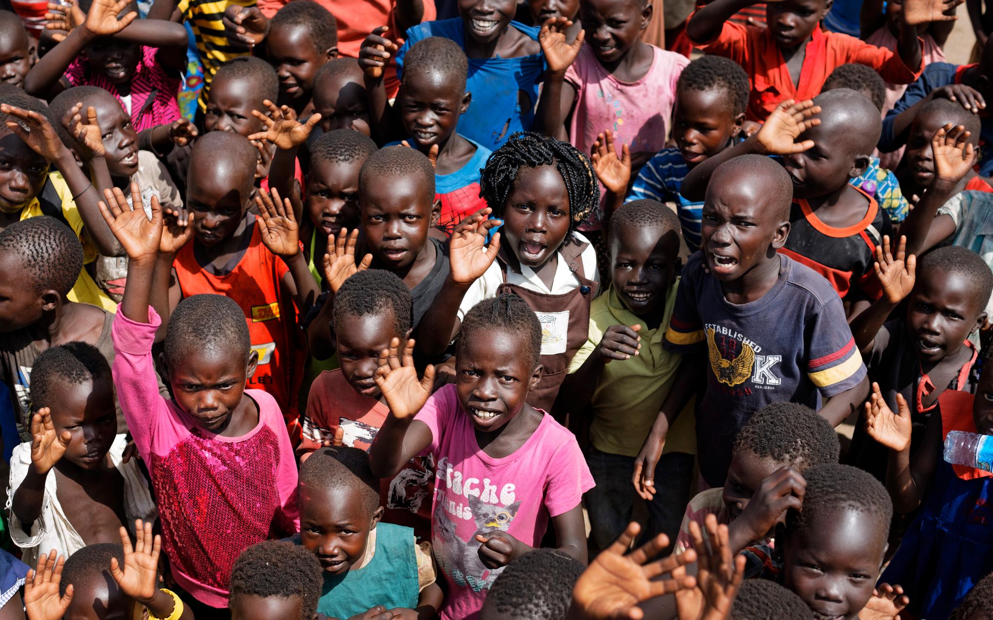   Sør-sudanske i flyktningbarn i leieren Bidi Bidi i Uganda ser opp og smiler til fotografen som flyr over det som er en av verdens største flyktningleirer. Leirens skole har 500 elever og får støtte fra UNICEF og Save the Children.