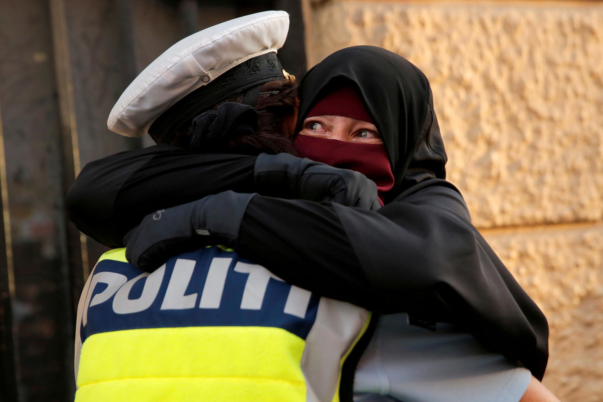 En politidame omfavner en kvinne i nikab under en demonstrasjon mot det danske forbudet mot nikab, burka og andre plagg som tildekker ansiktet.