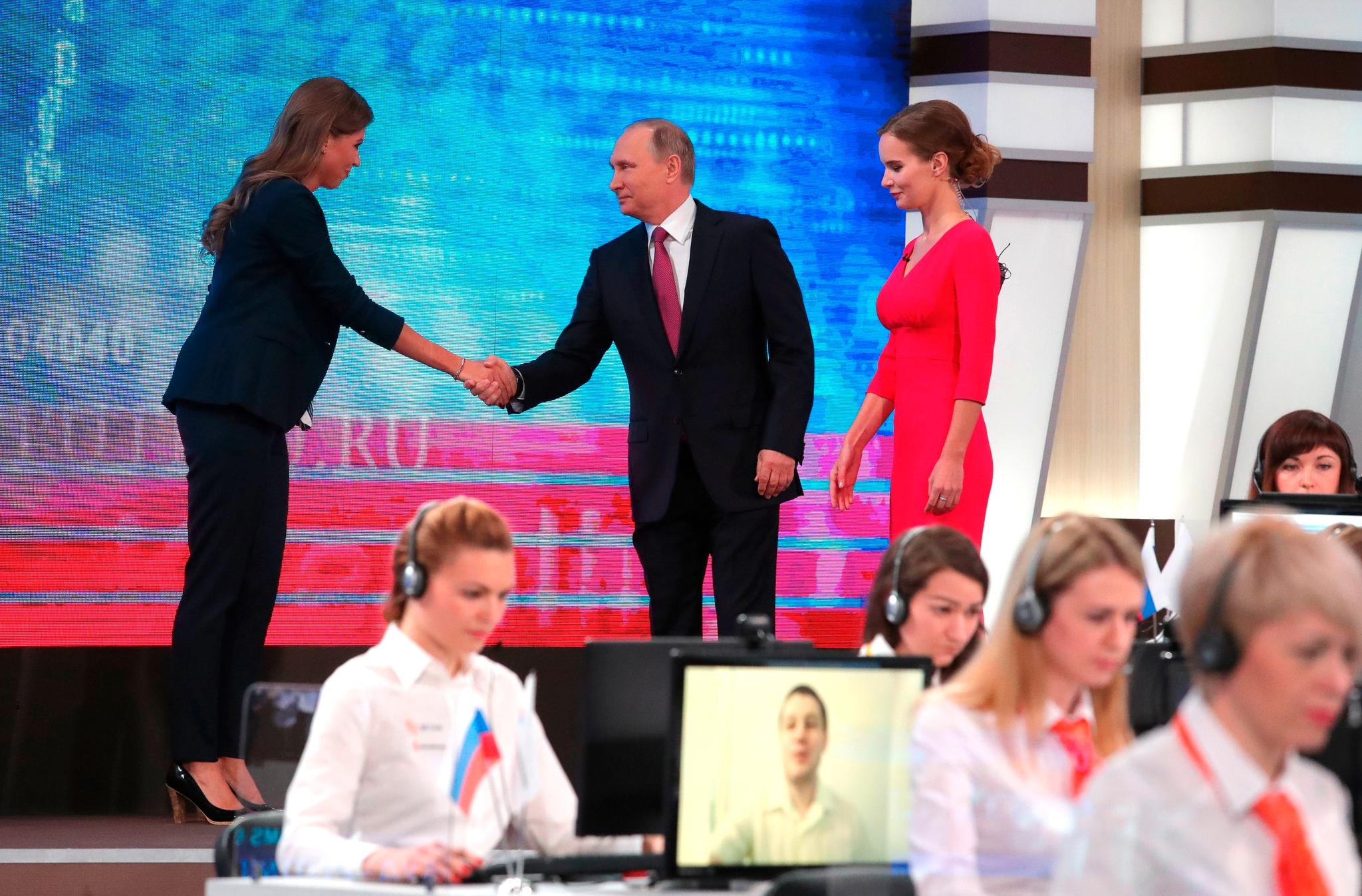  Putin bli tatt imot av en studiovertinne i rød kjole da han startet TV-showet «Direkte linje med Vladimir Putin» kl. 11 norsk tid i dag 