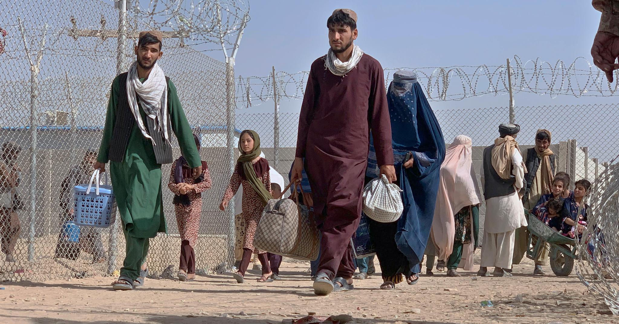 Afghanere går gjennom en sikkerhetssperring på vei inn i Chaman, Pakistan. De siste dagene har tusenvis av afghanere trukket mot grensen, én av få muligheter til å flykte fra Talibans Afghanistan. 