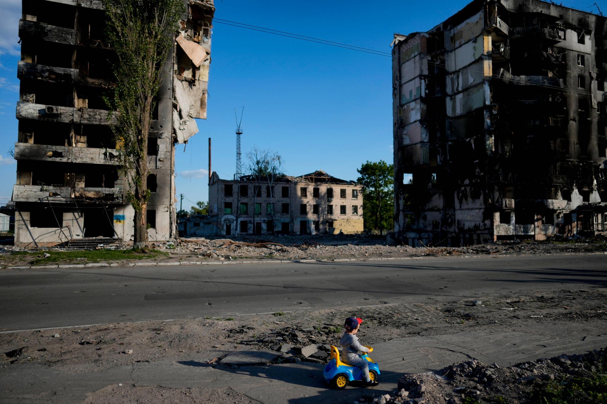 En gutt leker foran ødelagte hus i Borodjanka i Ukraina.