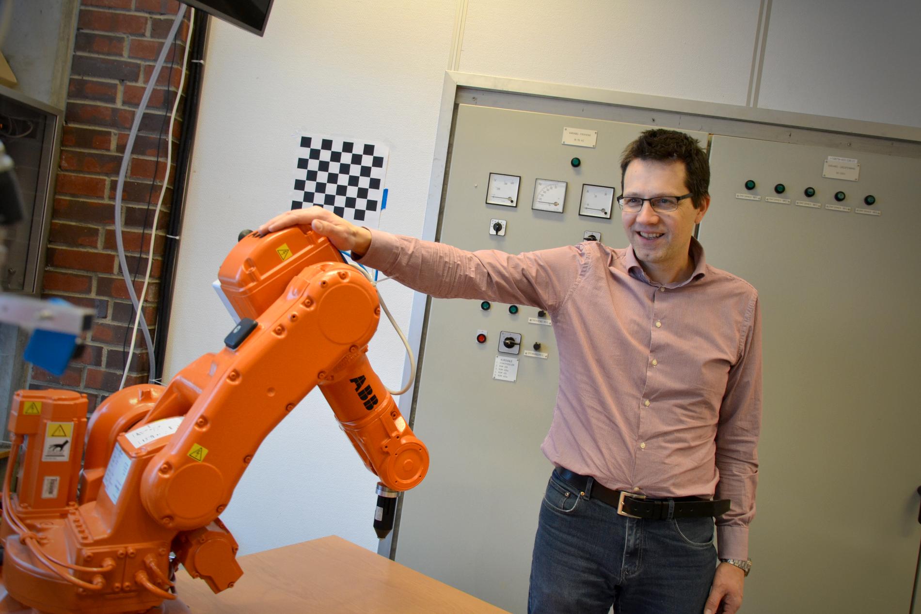 Instituttleder ved UiS Tom Ryen viser frem noen robotarmer studentene bruker i undervisningen. Disse er produsert på Bryne.