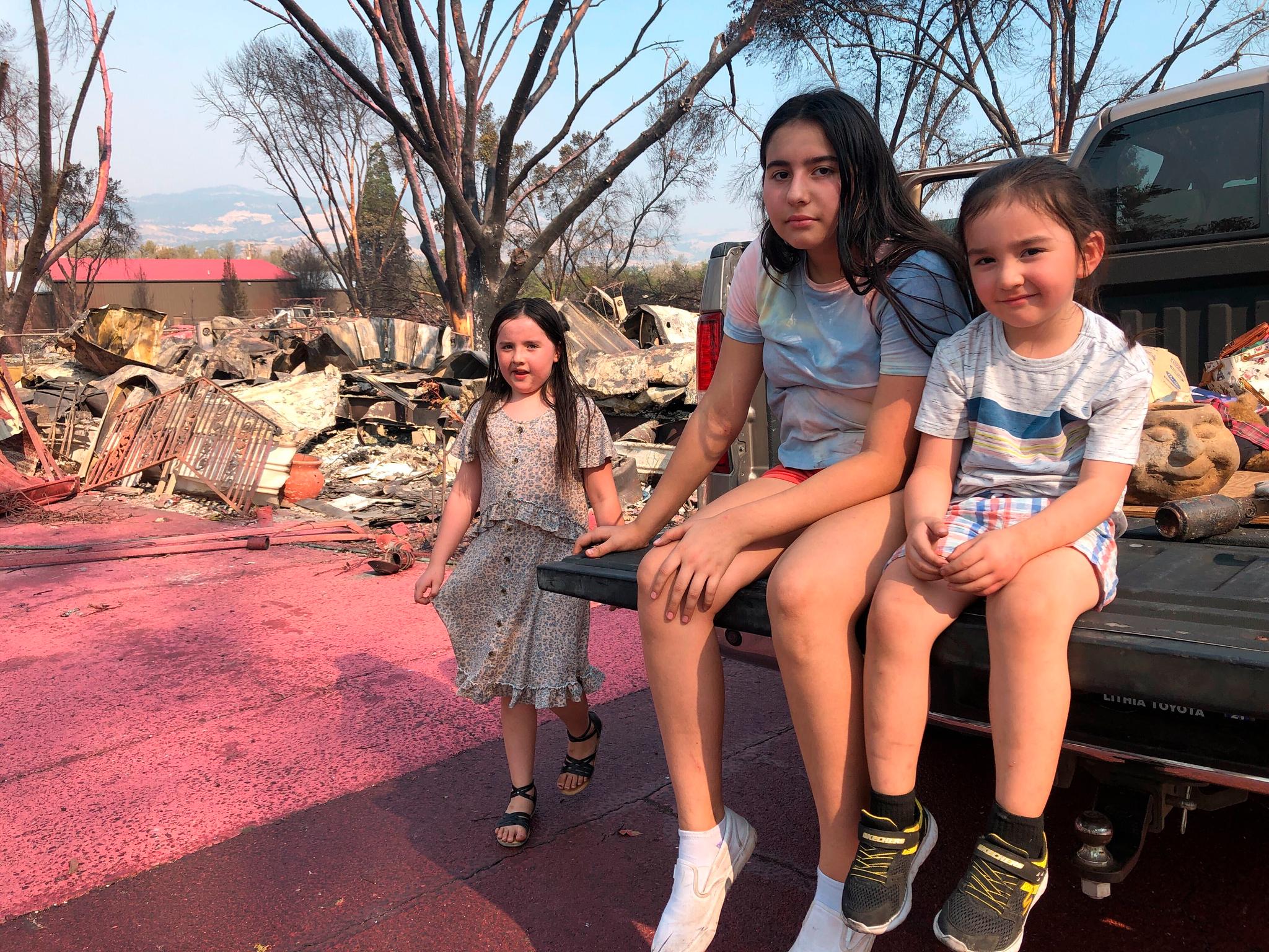Søsknene Italia Guterrez (9), Penelope Guterrez (13), og Thomas Guterrez (4), venter på at faren, Artemio Guterrez, redder noen få ting fra deres mobile hjem i Talent i delstaten Oregon.
