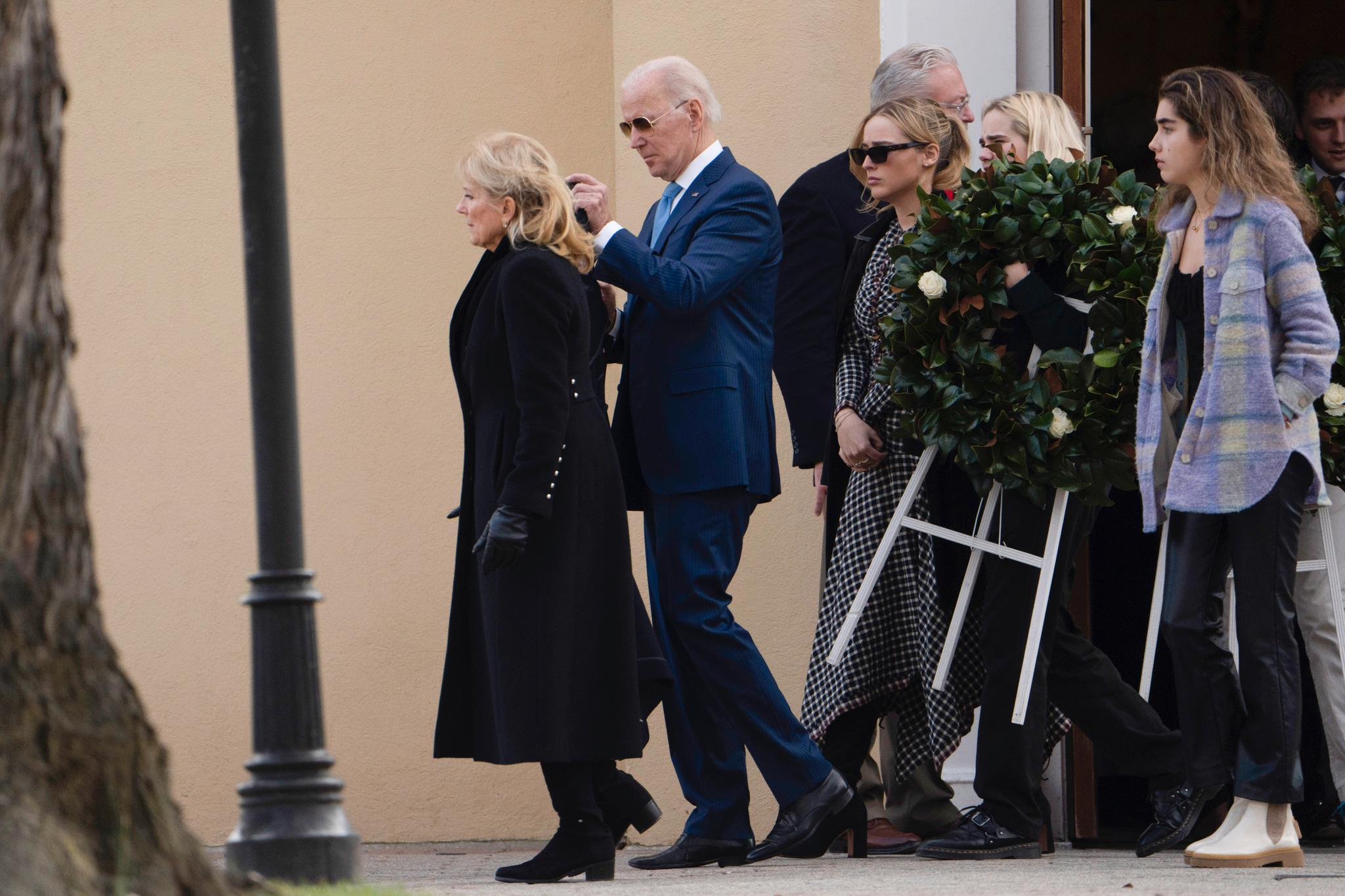 President Joe Biden og hans kone Jill fulgt av tre barnebarn med en krans etter gudstjenesten der de mintes Bidens første kone og lille datter som døde i en bilulykke for 50 år siden. 