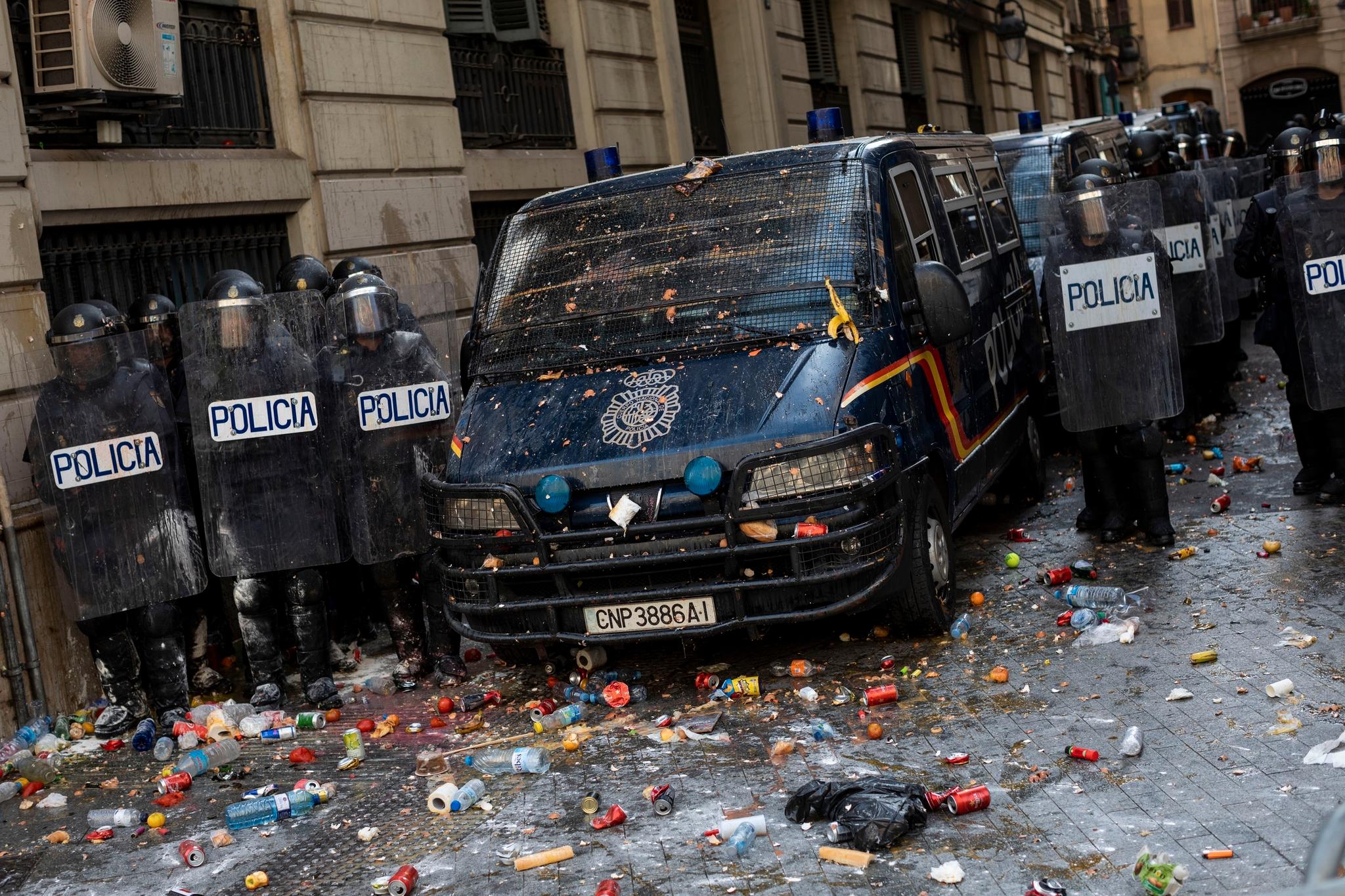 Spansk politi står utenfor en politistasjon som ble angrepet av rasende demonstranter fredag.