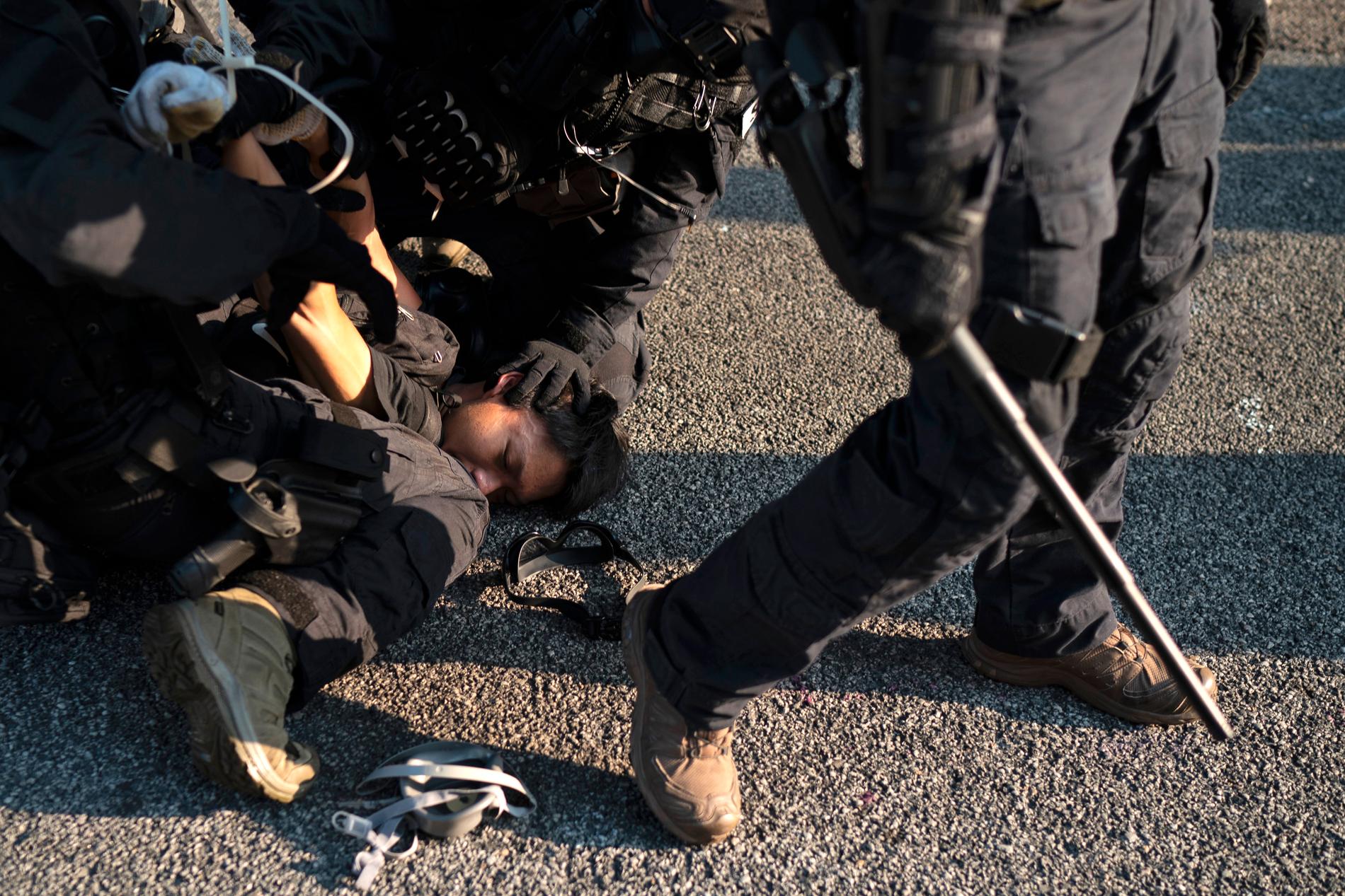 PÅGREPET: En demonstrant blir holdt nede og pågrepet under gatekampene i Hongkong.