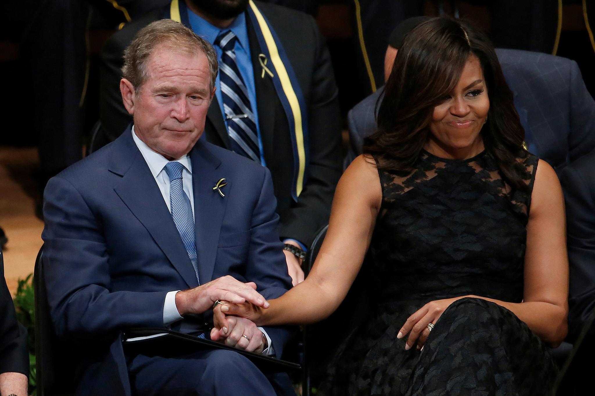 Tidligere president George W. Bush og Barack Obamas kone Michelle trøster hverandre under sørgehøytideligheten for de fem politimennene som ble drept i Dallas. Foto: Carlo Allegri / Reuters / NTB scanpix