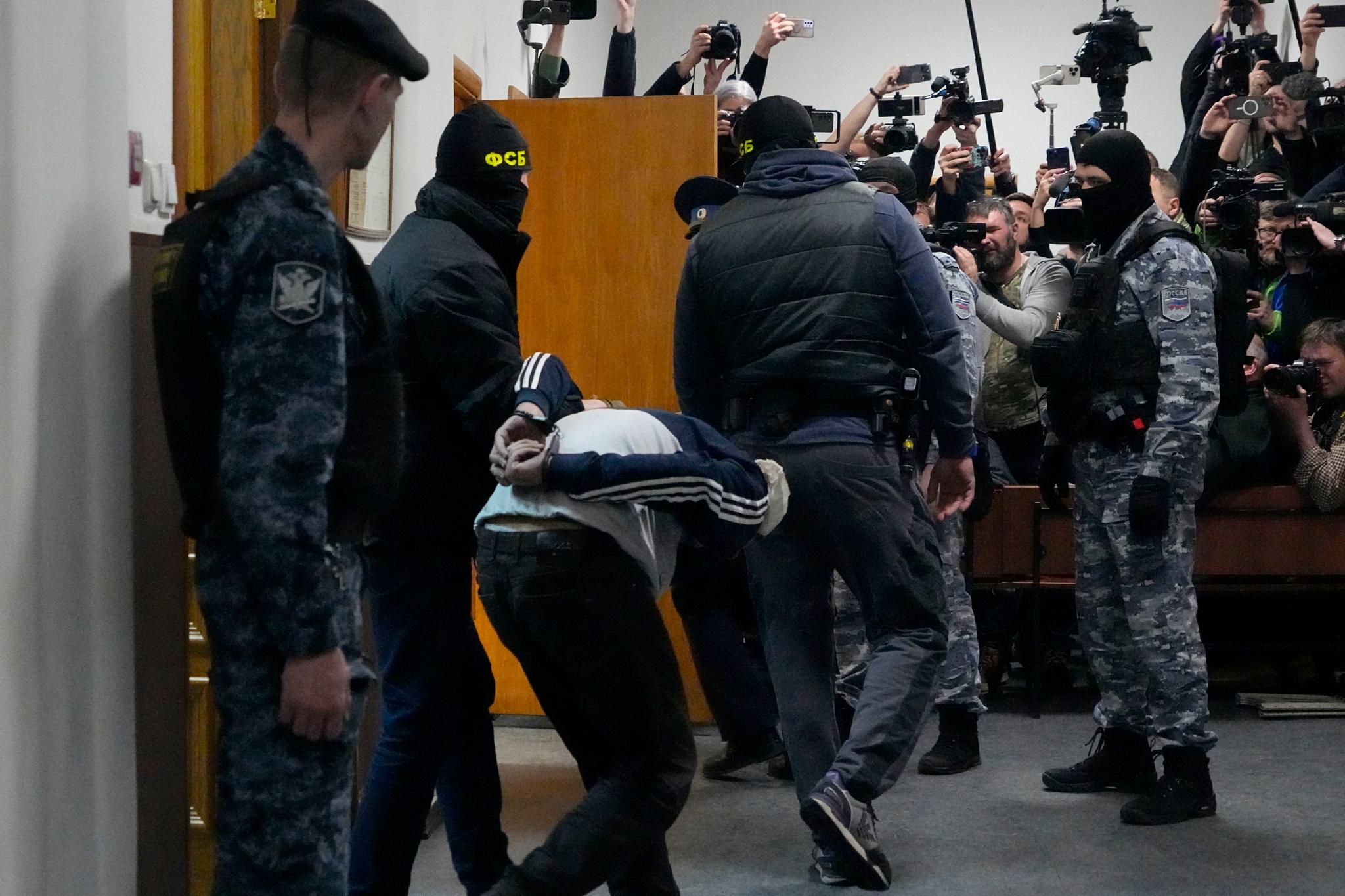 En av de mistenkte blir ført inn i retten i Moskva av politiet. 