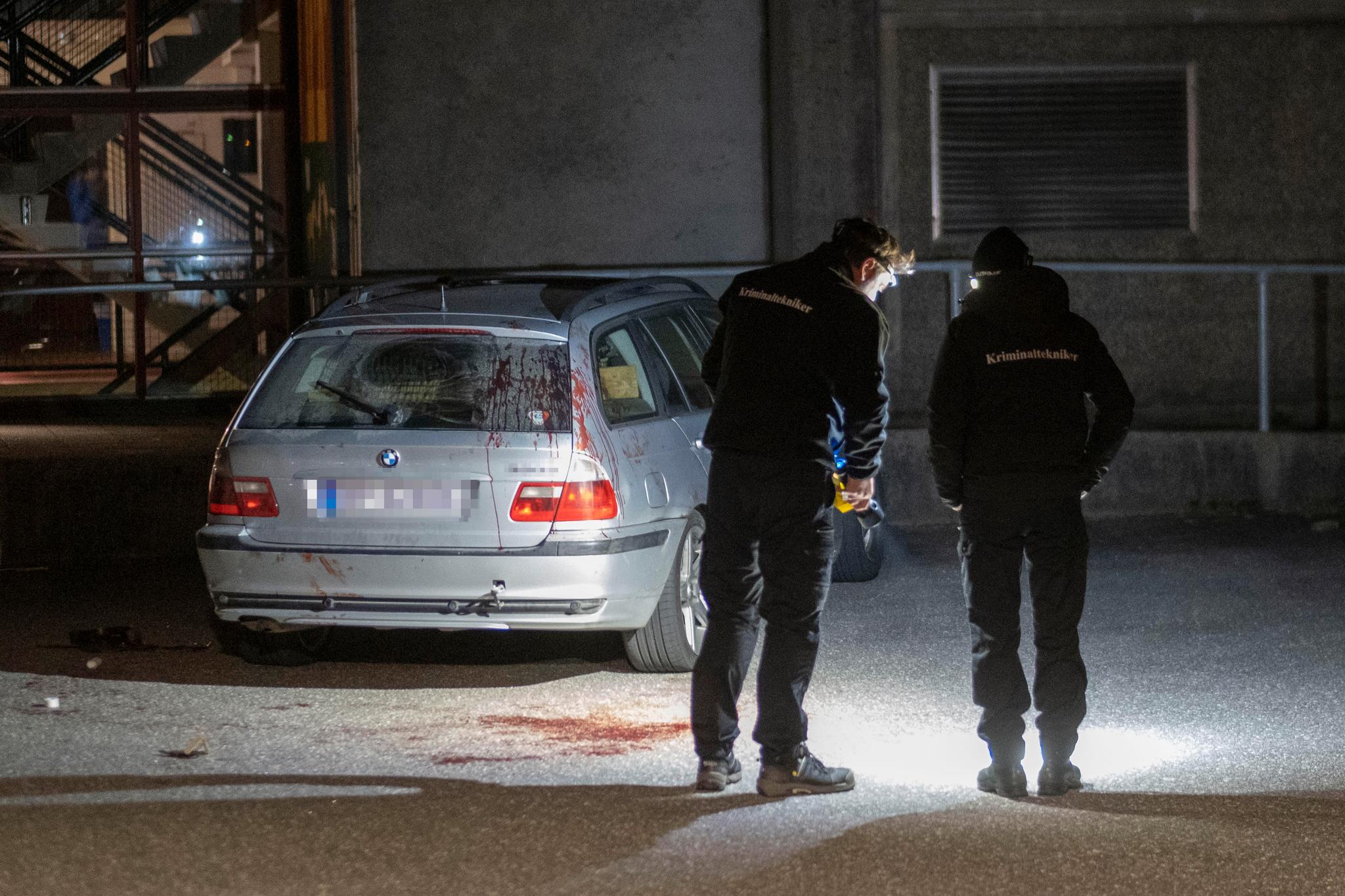 Kriminalteknikere fra politiet undersøker området rundt en bil parkert ved stedet der flere ble skadd i et masseslagsmål utenfor Lyngdalshallen tirsdag kveld. 