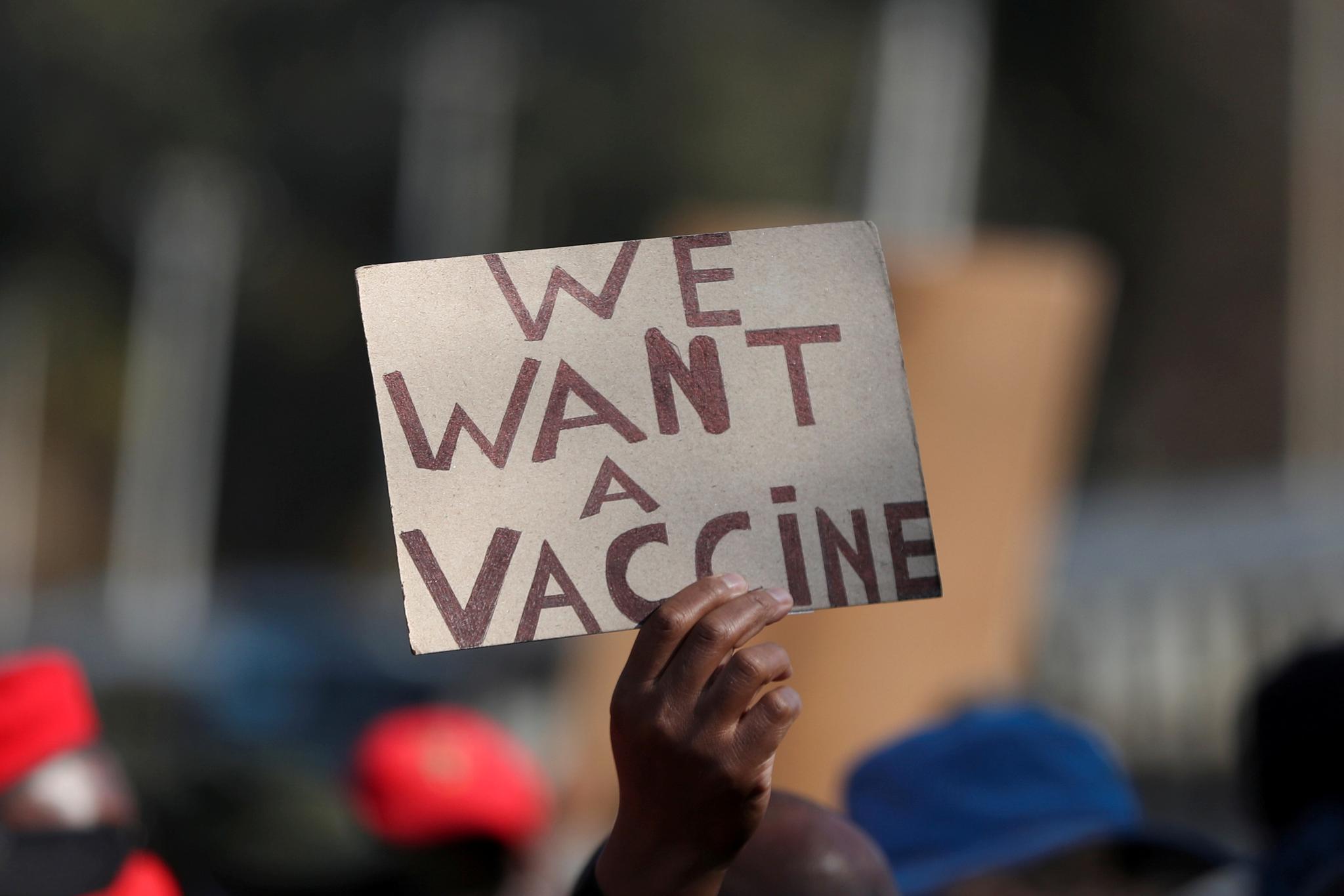 En person holder opp et skilt i protest mot skjevheten i den globale vaksinefordelingen. Bildet er tatt i Pretoria i Sør-Afrika i juni.
