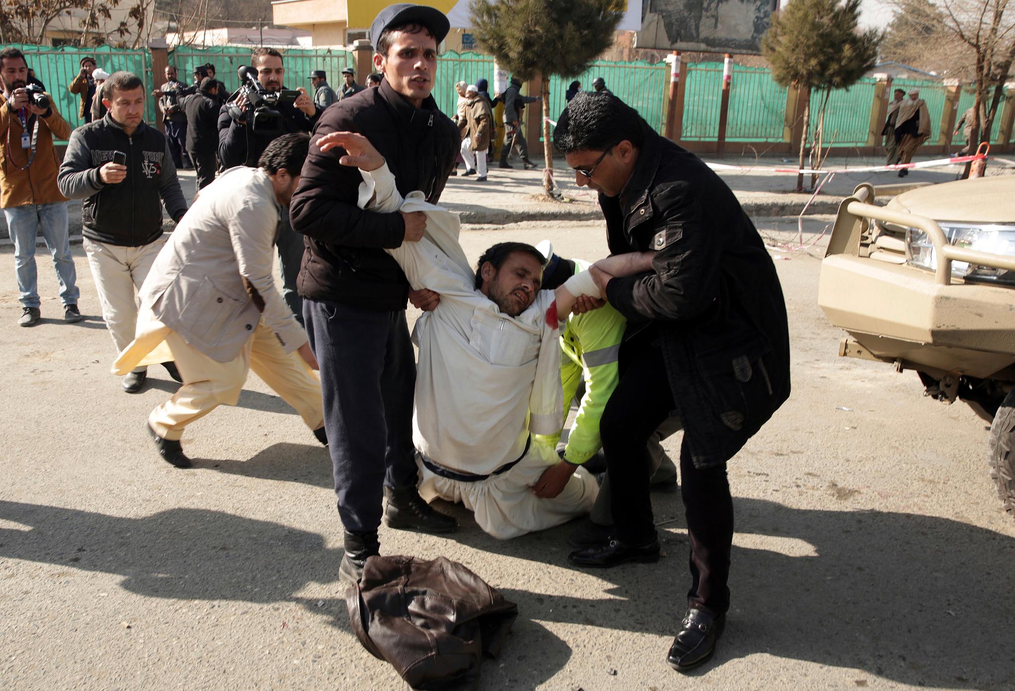 En såret mann hjelpes i sikkerhet etter å ha overlevd selvmordsangrepet i Kabul lørdag. 
