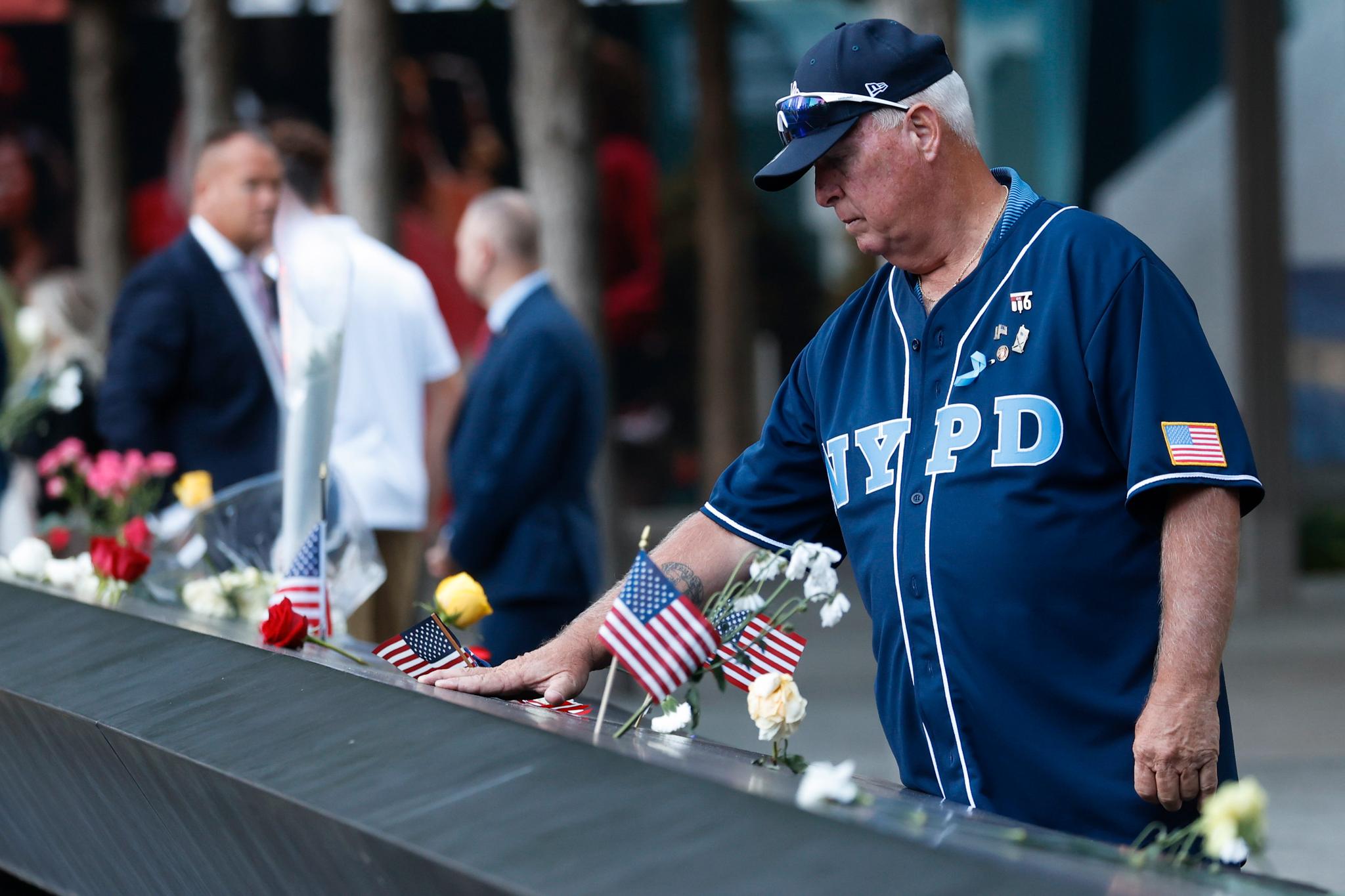 En sørgende mann iført en trøye med New York-politiets logo er møtt frem til minneseremonien. 