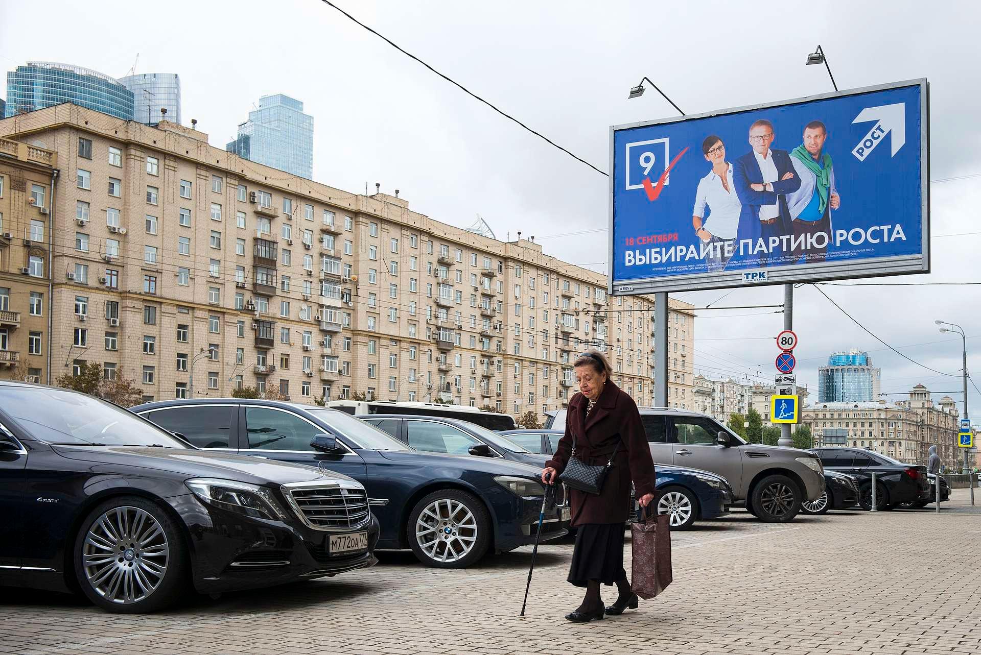 En russisk kvinne i sentrum av Moskva passerer en valgplakat. Konflikten med Vesten og krigen i Ukraina kommer langt ned på listen over ting russere nå er bekymret for.