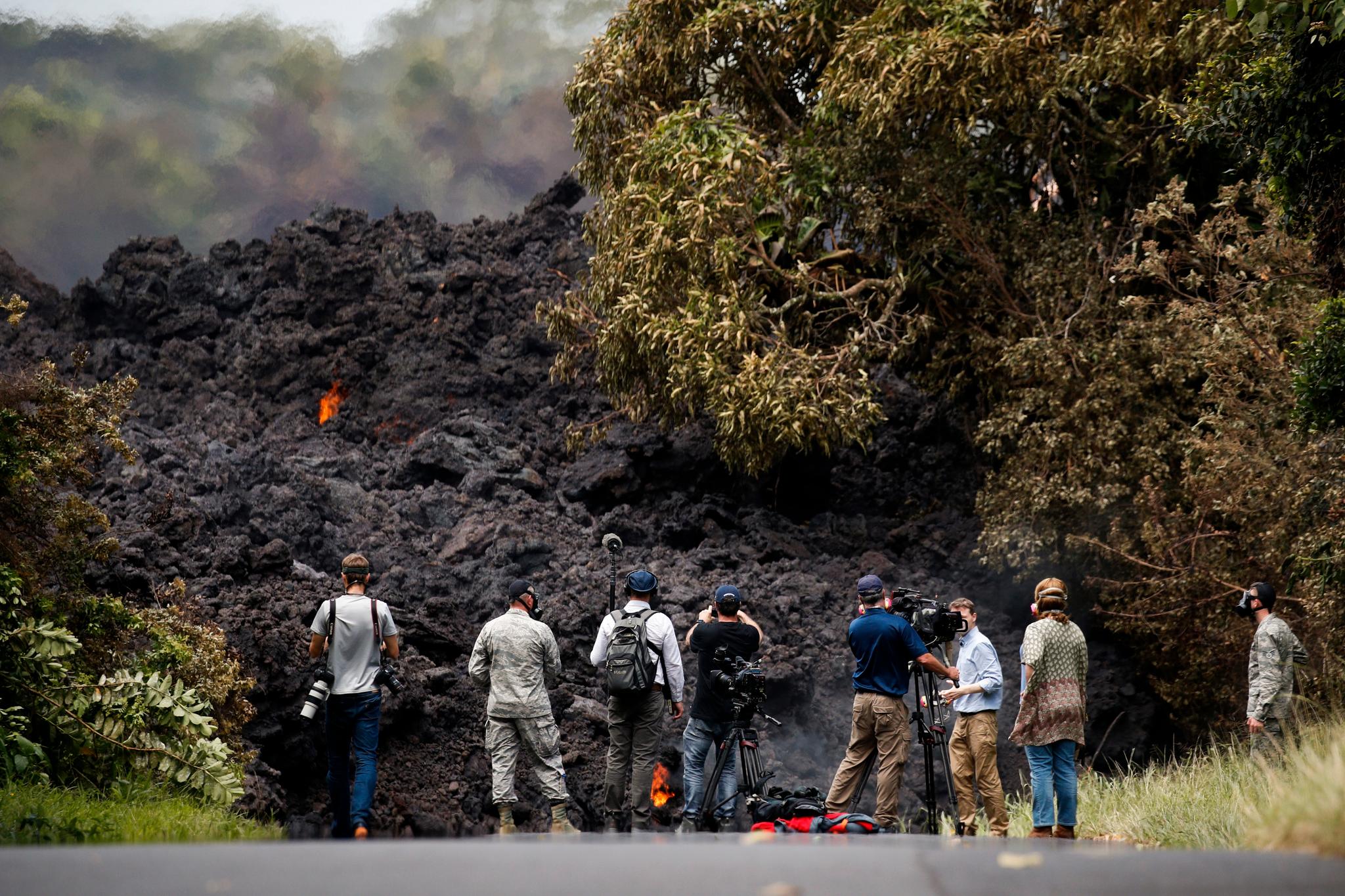 Journalister ser nærmere på en vegg av lava som har krysset veien på sin ferd mot havet ved Pahoa.
